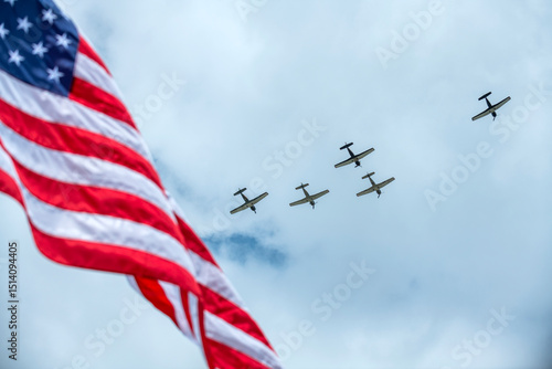 Planes fly over a Memorial Day event with the United States flag in the foreground