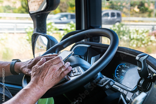 Senior truck driver’s hands texting on a mobile phone while driving,illegal, dangerous, and punishable.