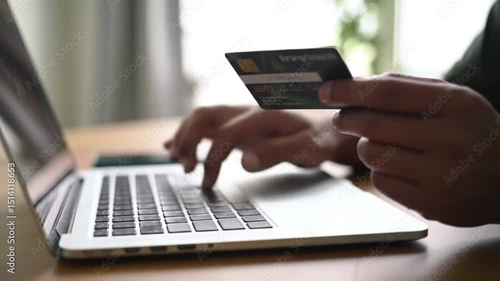 Person holding a credit card and typing on a laptop depicting an online transaction shopping and e-commerce. Person holding a credit card and typing on a laptop depicting an online transaction shopping and e-commerce.