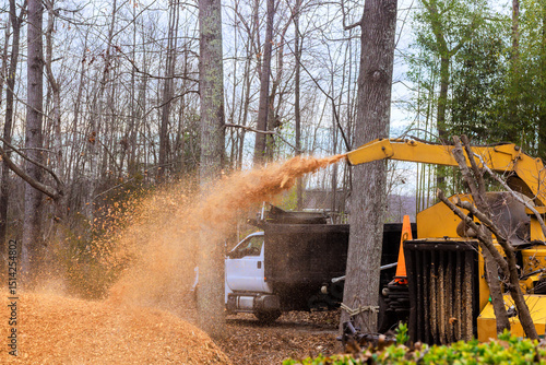 Foto Wood chipping machine processes logs into small wood chips amidst trees in fores