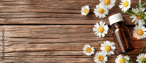 Chamomile flowers and amber bottle on rustic wood