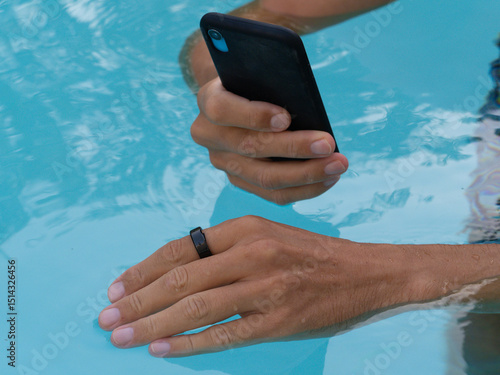 Hands in pool connect black smart ring health tracker to smartphone app.