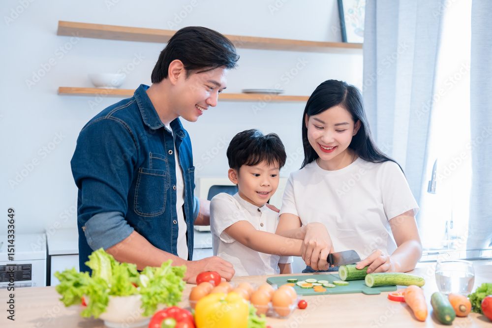 Naklejka premium Family cooking together in their kitchen mom showing son how to cut vegetables for dinner