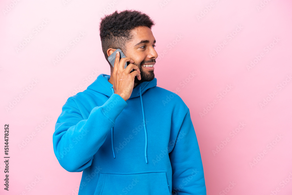Fototapeta premium Young Brazilian man isolated on pink background keeping a conversation with the mobile phone with someone