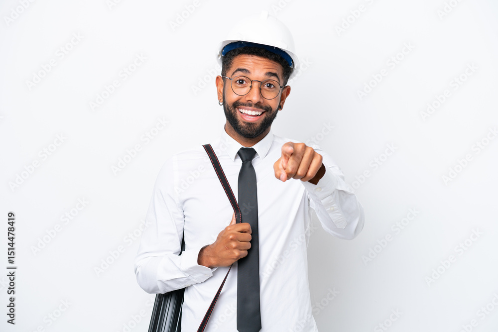 Young architect Brazilian man with helmet and holding blueprints isolated on white background surprised and pointing front Young architect Brazilian man with helmet and holding blueprints isolated on white background surprised and pointing front