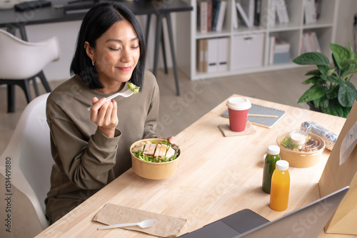 Bild auf Leinwand Asian woman eating healthy meal while working, Businesswoman having a lunch brea
