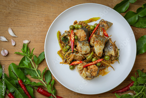 Fototapeta Naklejka Na Ścianę i Meble -  Spicy stir-fried catfish (Pad Cha Pla Dook) on a white plate, a popular and flavorful Thai dish. The dish features pieces of catfish stir-fried with herbs, spices, chili peppers and Original Thai food