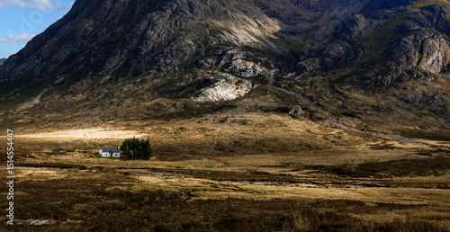 A little white house sitting in the shadow of the epic mountains in Scotland.