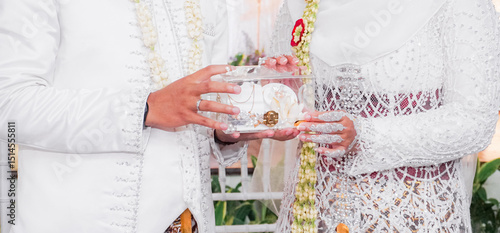 Canvas Print Bride and groom exchanging rings during a traditional Indonesian wedding ceremony, symbolizing their commitment and love