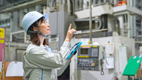 Obraz na płótnie タブレットを持って工場機械を点検する女性作業員