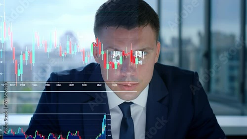 Focused businessman analyzing financial data on transparent screen with trading charts and graphs, working in a modern office with a city view.
