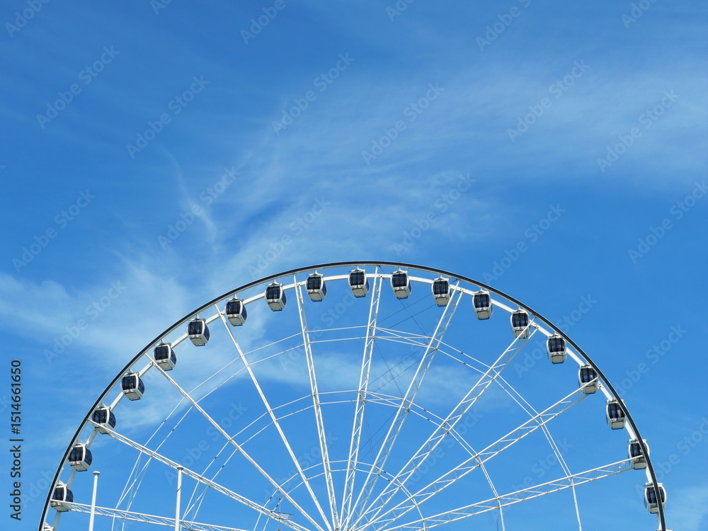 Large white Ferris wheel with closed gondolas against clear sky. Eye-catching geometry, strong subject for design and engineering fans. Copy space. Space for texts and designs. Large white Ferris wheel with closed gondolas against clear sky. Eye-catching geometry, strong subject for design and engineering fans. Copy space. Space for texts and designs.