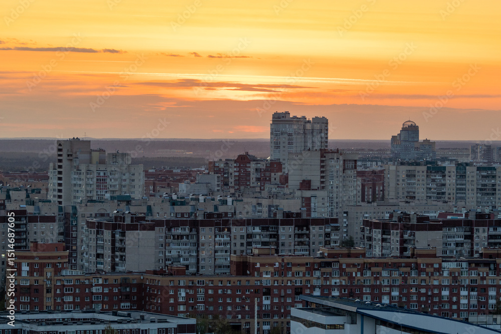 Fototapeta premium urban landscape is illuminated by the orange and pink shades of sunset. Tall and imposing buildings create a sense of awe and wonder. Top view of a multi-storey building.