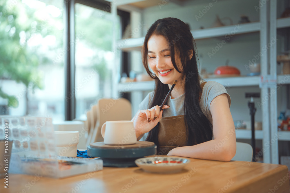 Happy asian woman thinking of creative cup painting and product design ideas with handmade ceramic mug at pottery studio – smiling small business owner in artisan clay workshop interior Happy asian woman thinking of creative cup painting and product design ideas with handmade ceramic mug at pottery studio – smiling small business owner in artisan clay workshop interior