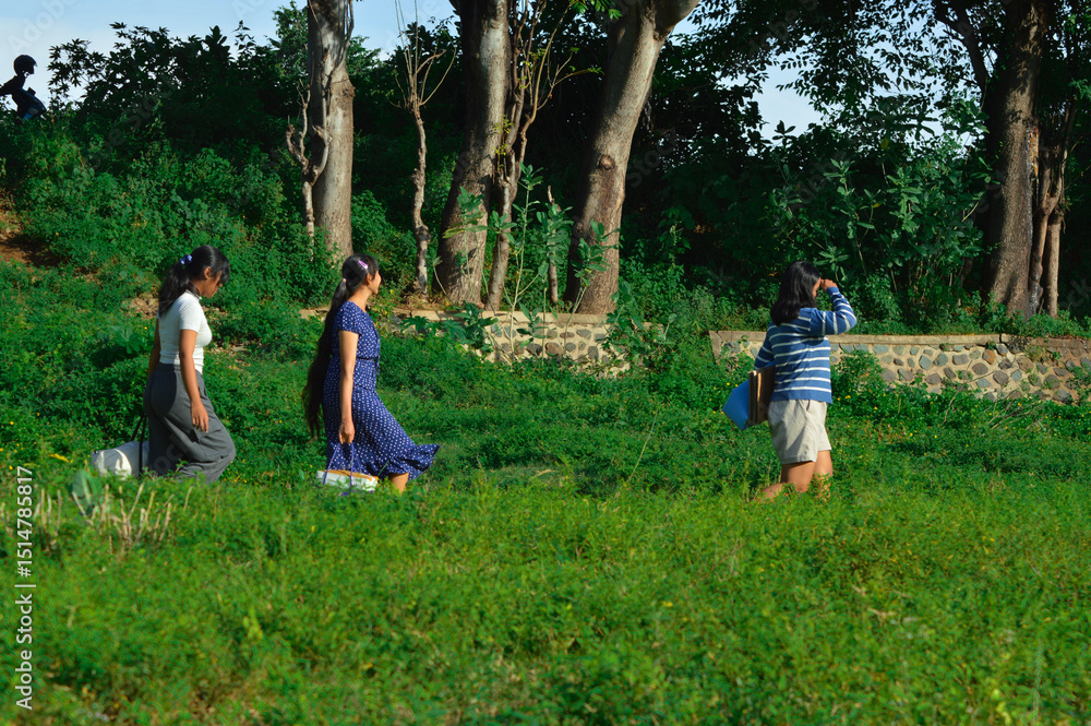 Fototapeta premium As they move along a narrow footpath, the girls take their time scanning the area, staying alert and observing their environment in search of a suitable camping spot.