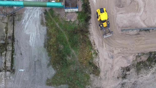 Top-Down View of Yellow Excavator Sorting Sand and Gravel in Industrial Storage Yard