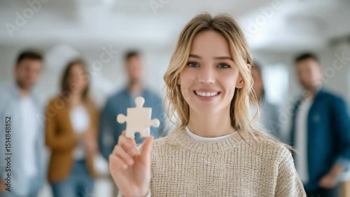 Wallpaper Mural Business Vision: A smiling young woman holds a puzzle piece, embodying a solution or the concept of teamwork. Behind her, a team stands, slightly out of focus, representing collaboration. Torontodigital.ca