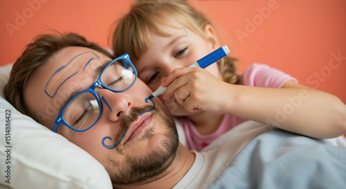Daughter drawing funny glasses and mustache on sleeping father's face with blue marker. Playful prank moment showing childhood creativity and intimate family humor during Father's Day relaxation time