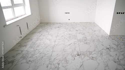 Foto Construction worker installing large marble tiles on the floor using tile spacer