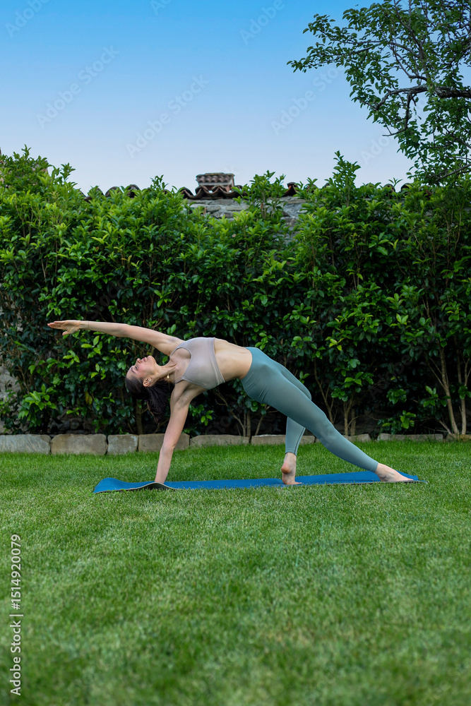 Fototapeta premium young woman yoga instructor doing exercice on mat on the grass
