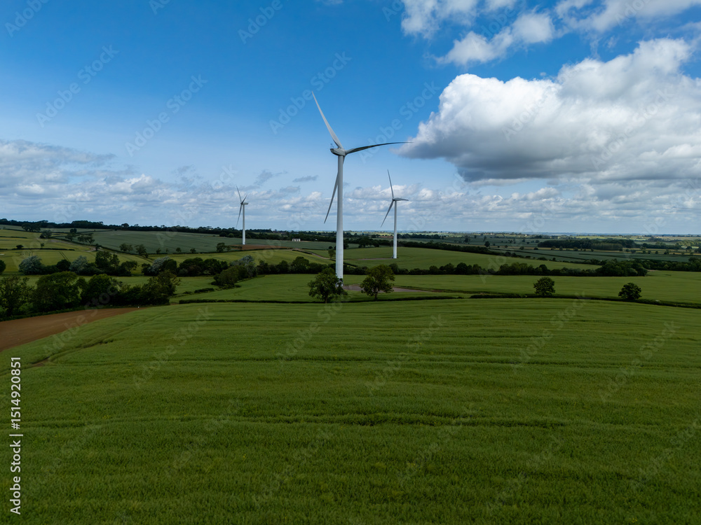 Obraz premium Wind turbines generating clean energy in green field under blue sky