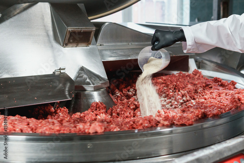 Processing of production minced meat in industrial meat grinder, close up.