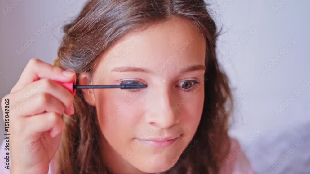 Young girl applying mascara in a bright room while getting ready for a special occasion, showcasing a makeup routine Young girl applying mascara in a bright room while getting ready for a special occasion, showcasing a makeup routine