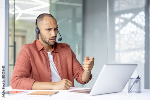 A man with a headset gestures emphatically during a video call, expressing surprise and consternation with his facial expression.