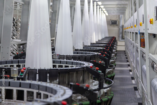 Interior of a factory shop. A series of equipment for weaving polypropylene fabric for construction bags in perspective. Processing of raw materials. Without people.