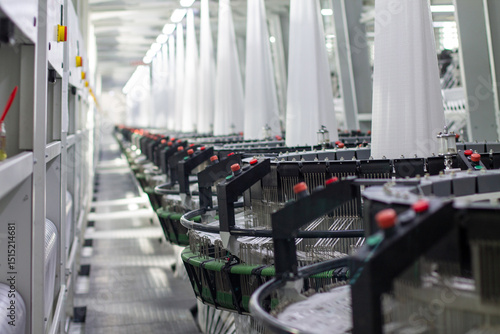 Interior of a factory shop. A series of equipment for weaving polypropylene fabric for construction bags in perspective. Processing of raw materials. Without people.