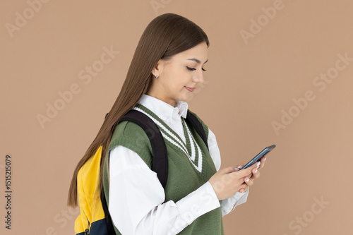 Photo of young caucasian college girl with backpack and smartphone on brown background