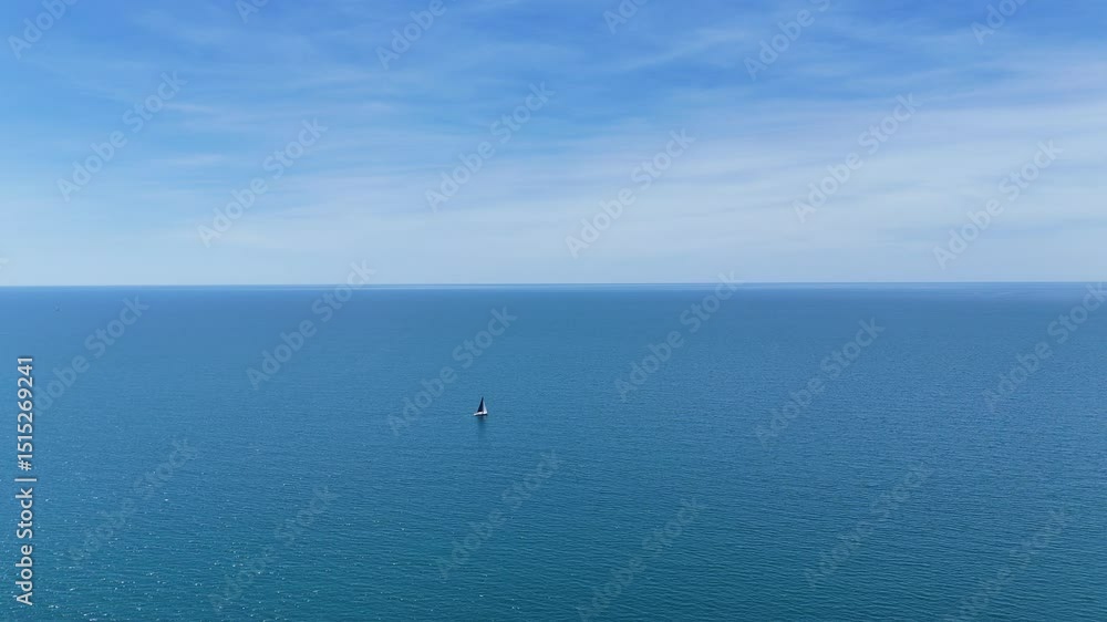 Lone Sailboat Floating in Vast Open Sea Under Serene Blue Sky Lone Sailboat Floating in Vast Open Sea Under Serene Blue Sky