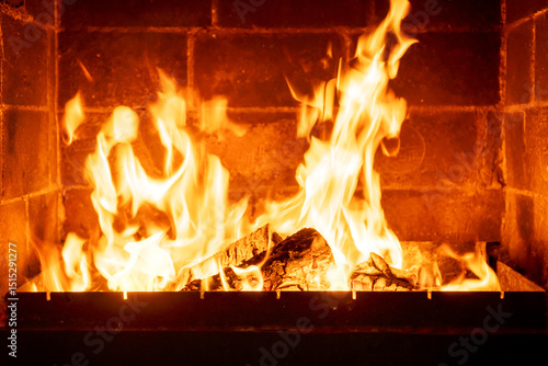 Closeup fire inside traditional fireplace  orange flames dancing  rustic home setting  cozy winter scene  warm lighting effect  evening cabin comfort