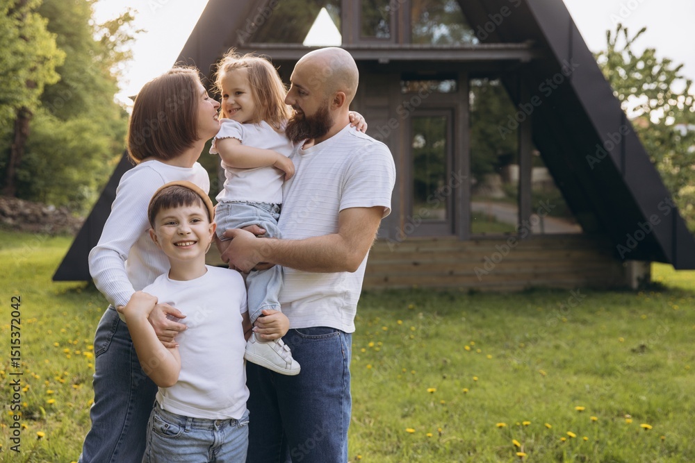 Fototapeta premium Happy family embracing in front of their modern a frame house