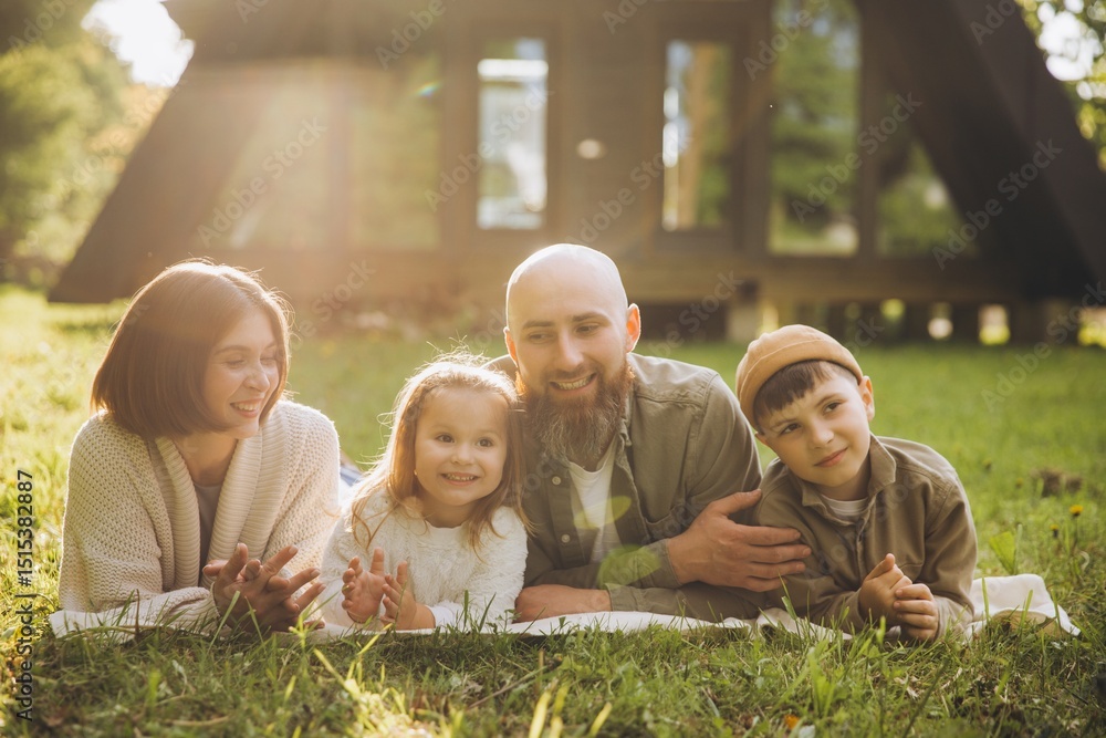 Φωτογραφία Happy family lying on grass enjoying weekend together in front of their modern a