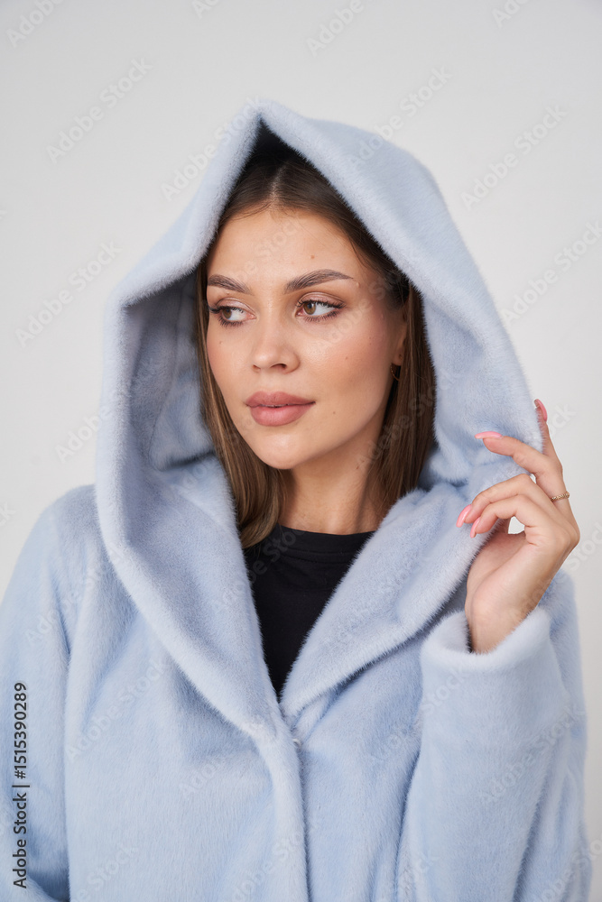 Obraz premium A cheerful brunette woman wears a light blue hoodie with a hood pulled back