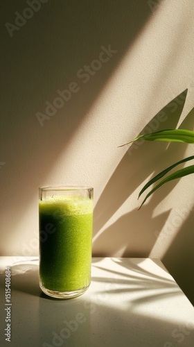 Refreshing Green Smoothie in a Glass on a White Table With Sunlight Casting S...