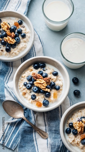 Breakfast Bowl With Oatmeal, Blueberries, and Nuts Served With Milk on a Table