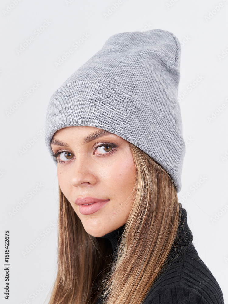 Fototapeta premium Brunette woman wearing a stylish gray beanie smiles cheerfully against a white background