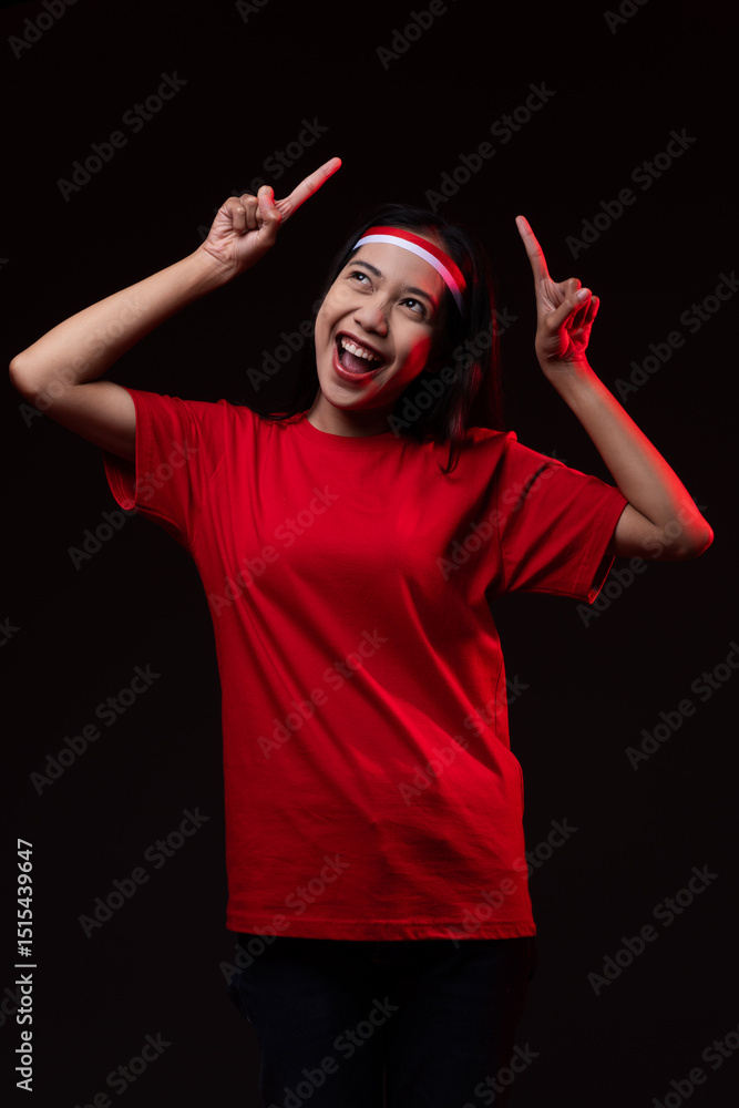 Fototapeta premium Portrait of Young Asian Woman Pointing Up Wearing Red Outfit, Indonesian Independence Day Concept