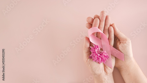 Hands holding pink ribbon and flower, Breast cancer awareness and October Pink day, world cancer day