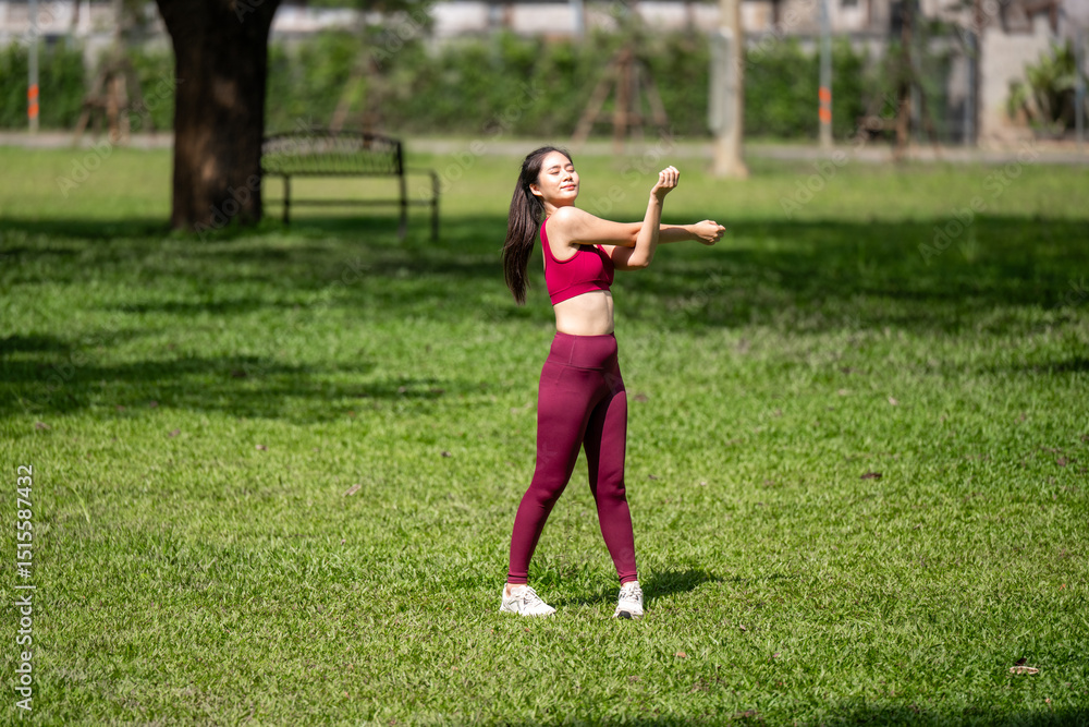 A woman in a red top and black pants is stretching in a park A woman in a red top and black pants is stretching in a park