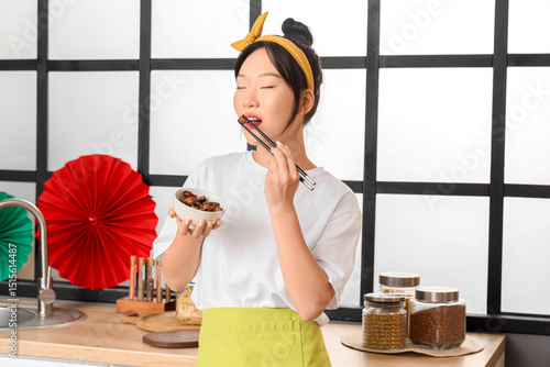 Young Asian woman eating ta...