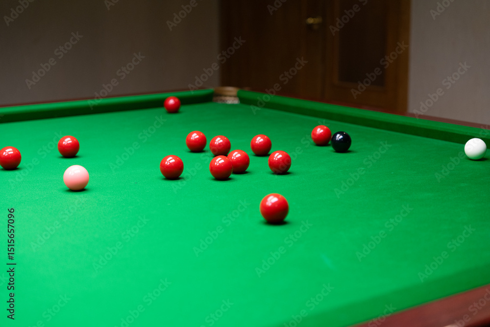 A snooker table with red, black, pink, and white balls scattered A snooker table with red, black, pink, and white balls scattered