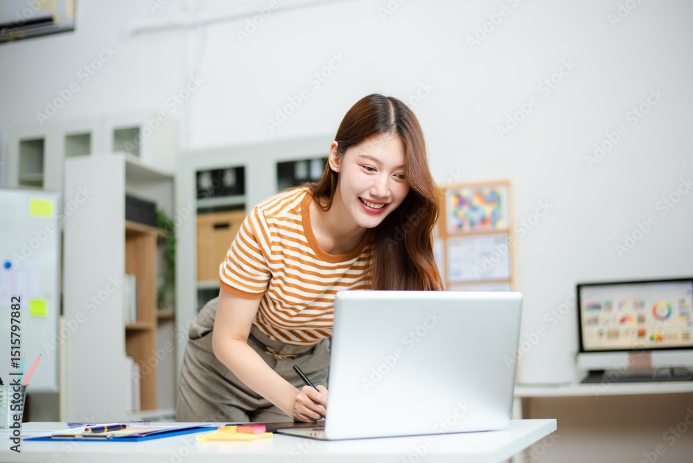 Fototapeta premium Smiling designer working on colorful branding and chart plans at desk with laptop and color swatches.