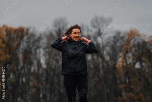 Photos Sportswoman putting on hood in a park during autumn