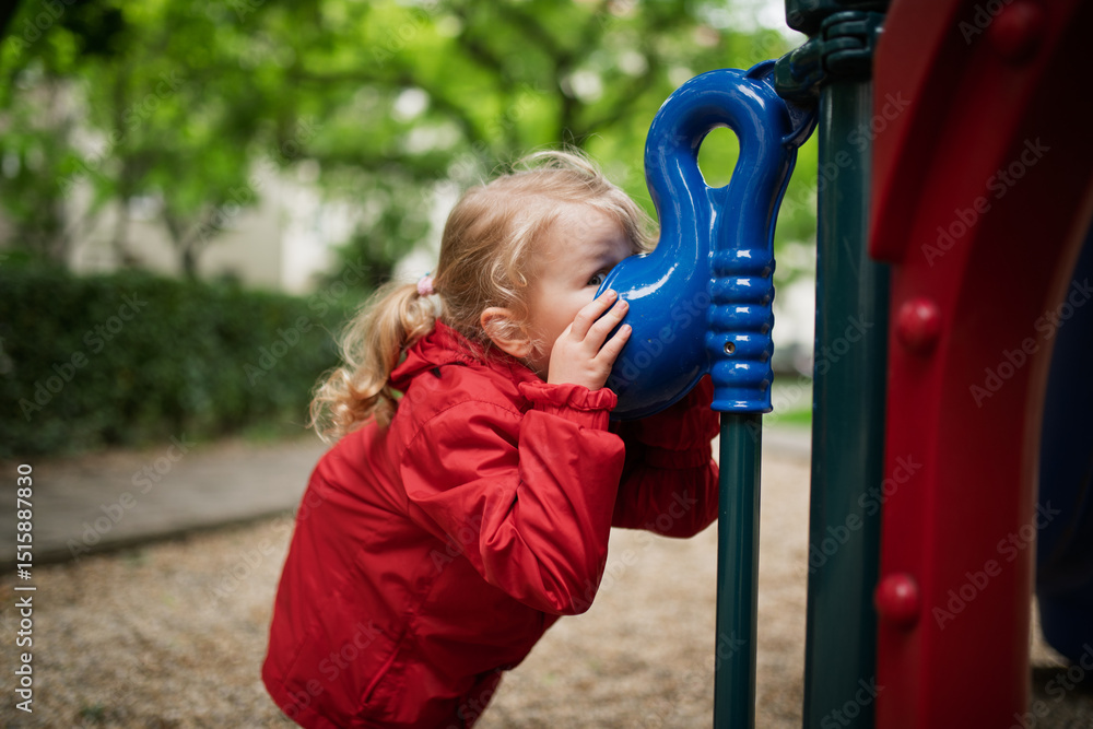 Obraz premium Curious girl peeking through playground tube