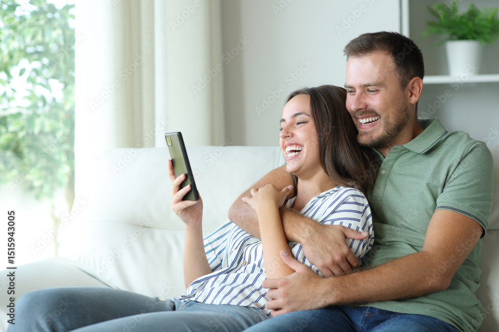 Fototapeta premium Happy couple enjoying watching media on mobile phone
