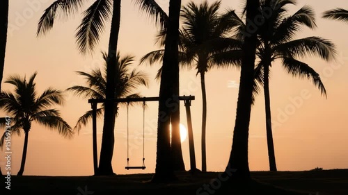 A cinematic sunset beach scene with tall palm trees and a swing, the camera slowly panning from left to right. The golden light of the setting sun casts long dramatic shadows across the sand