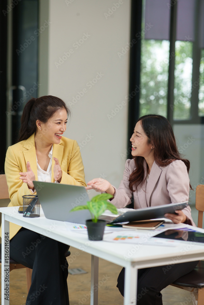 Obraz premium Group of two Asian businesswomen using laptops and tablets having a meeting about working together.